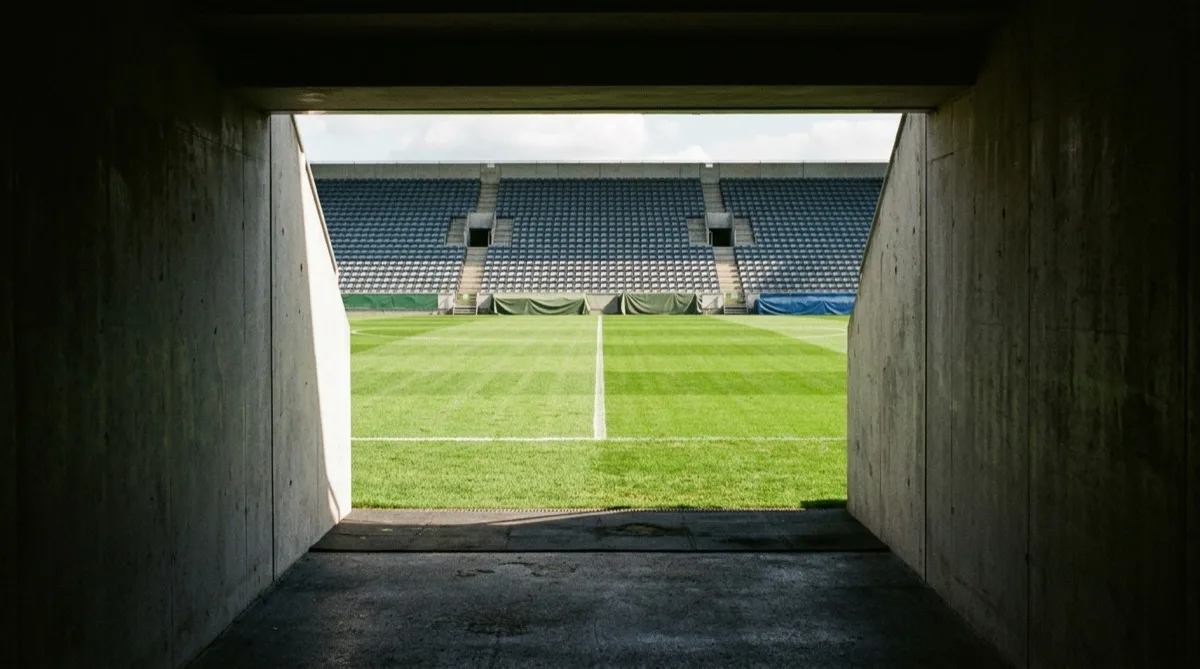 The view from inside a stadium players' tunnel out onto an empty green football pitch