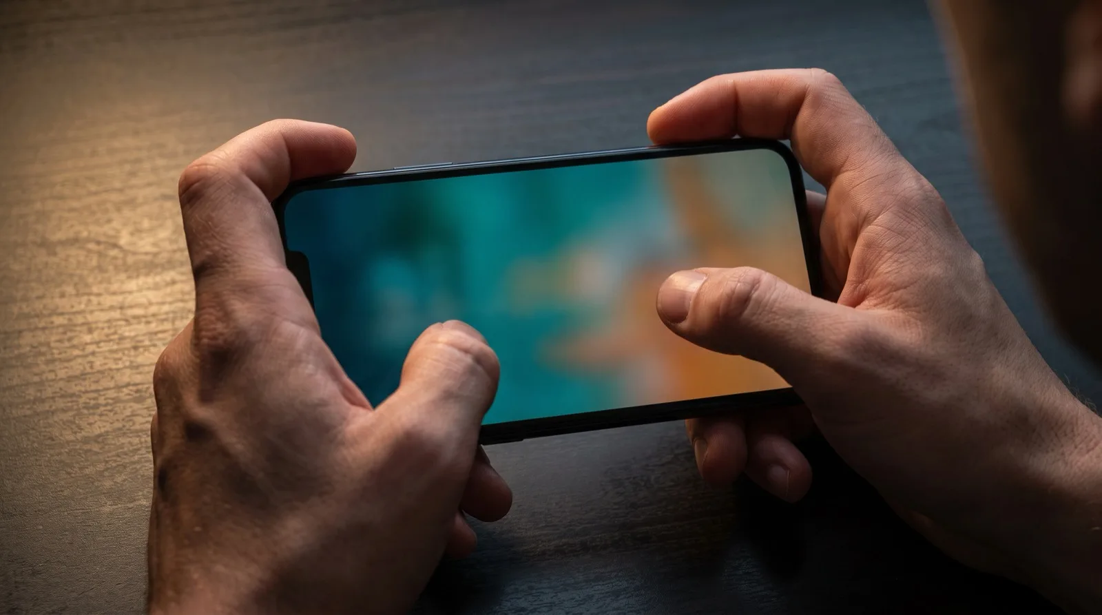 A four-finger claw grip on a smartphone, index fingers over the top edge and thumbs on the lower screen