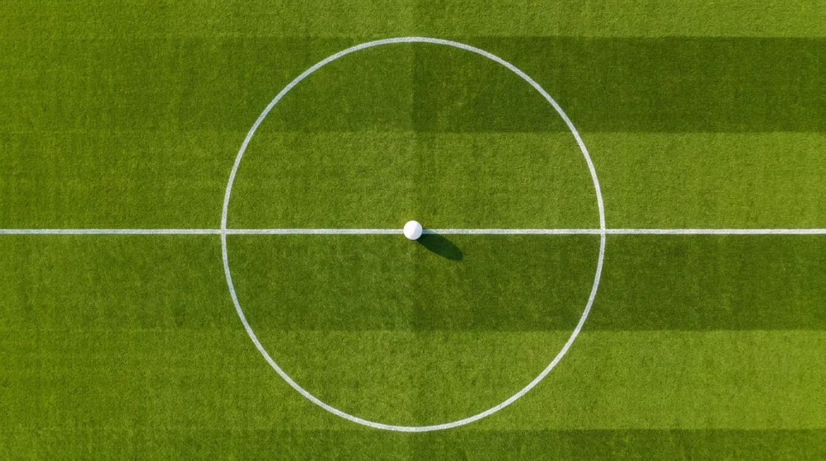 Overhead view of a football centre circle with a white ball on the centre spot