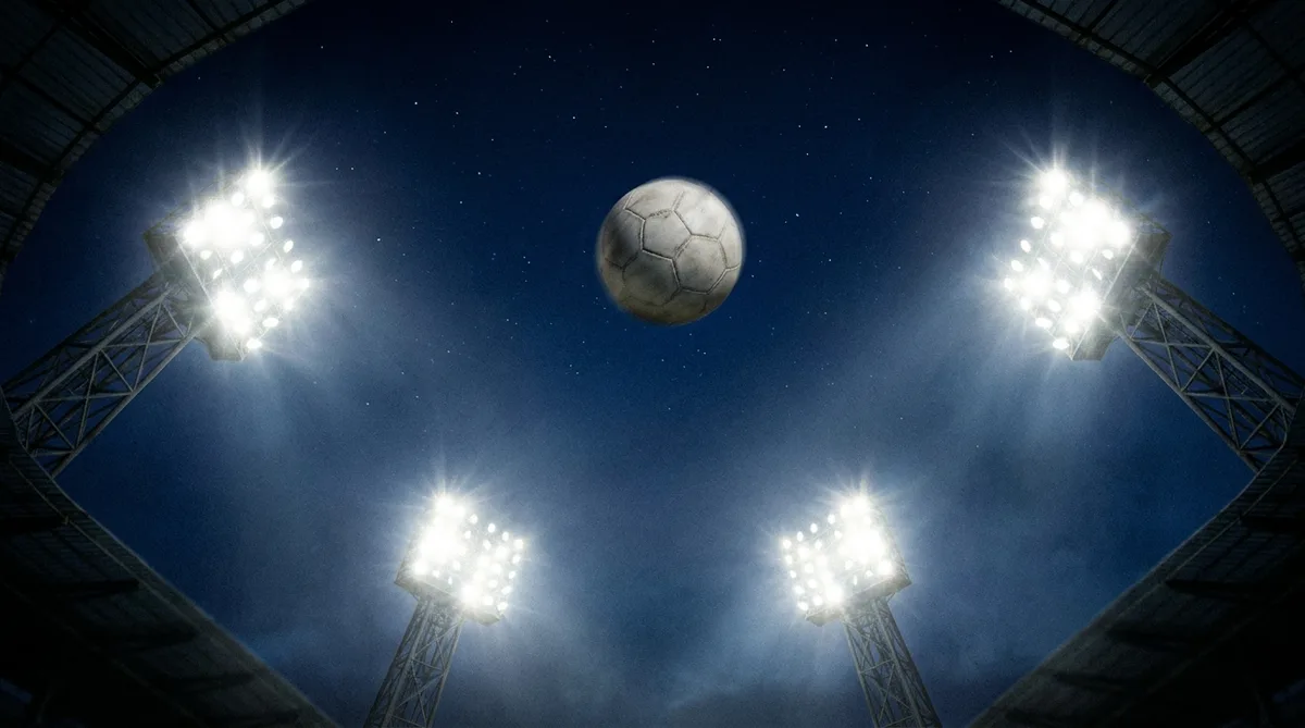 A football high in the air seen from below against stadium floodlights at night