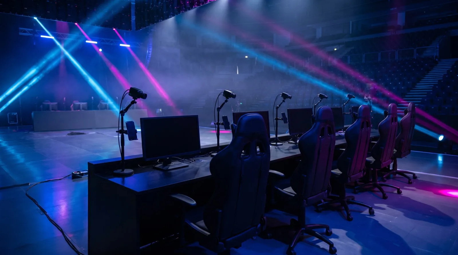 An empty mobile esports arena stage with phone stands and gaming chairs under blue and magenta lighting