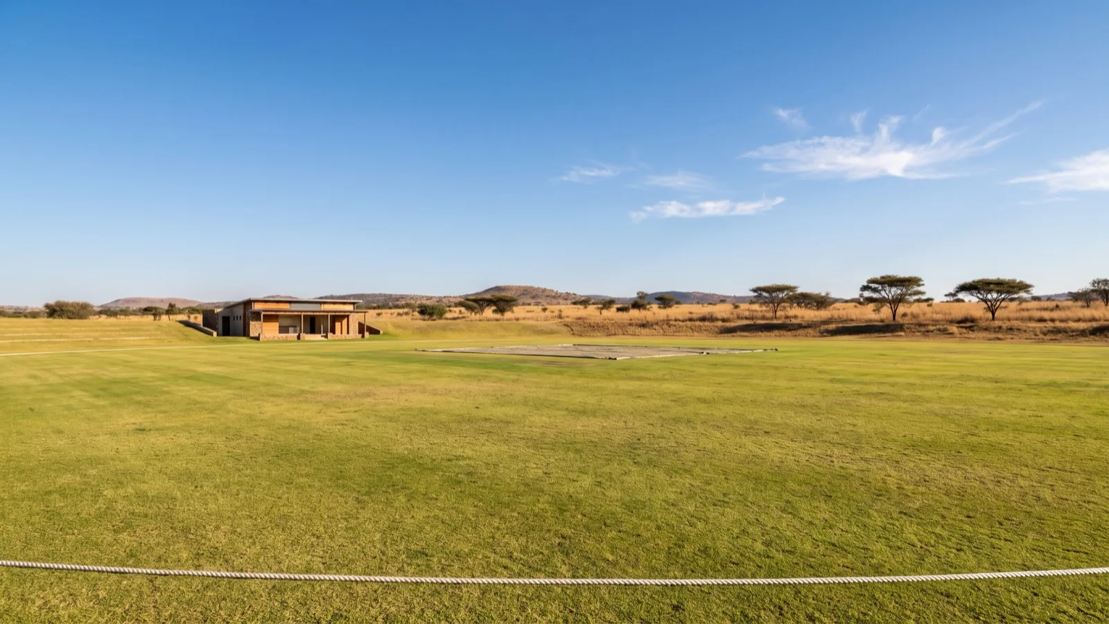 Cricket ground with a boundary rope and pavilion set in a dry southern African landscape