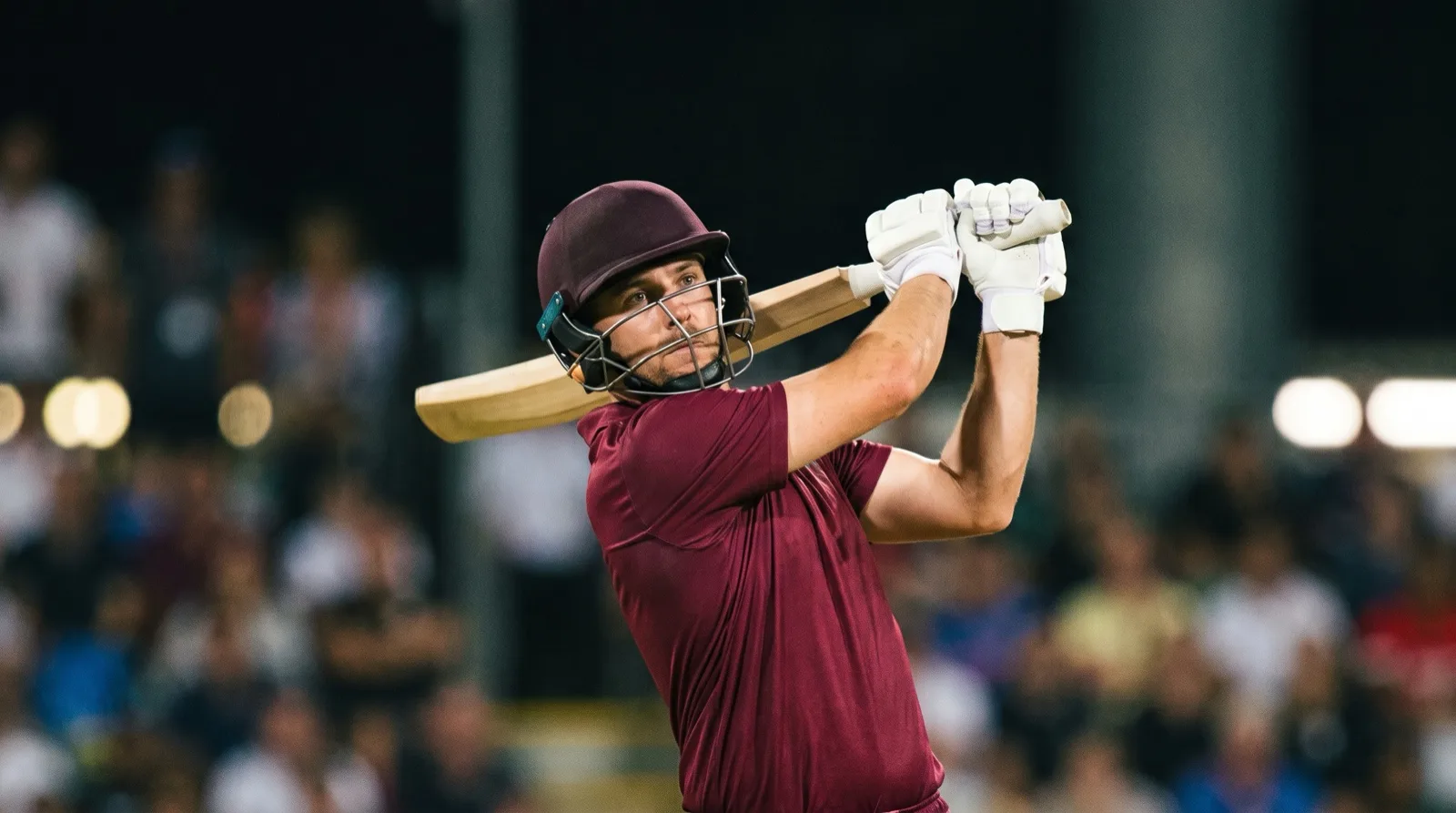 Batsman following through after a big shot under floodlights at a T20 World Cup match