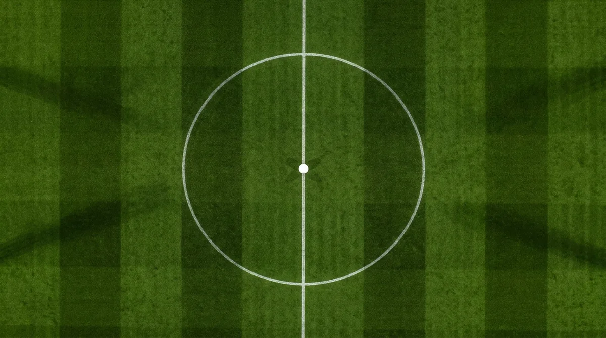 The centre circle and centre spot of a floodlit football pitch seen from directly above